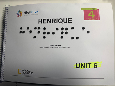 The cover of a work book with the name "Henrique" on it in both print and braille