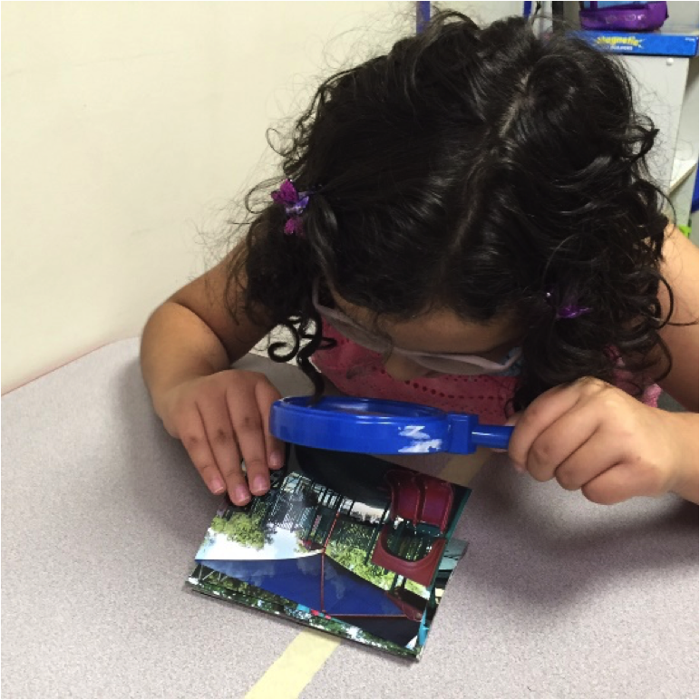 Student examining photos with a handheld magnifier