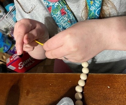 Student stringing wooden beads.