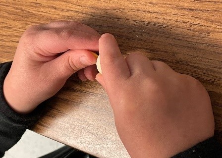 Student's hands stringing the wooden beads.