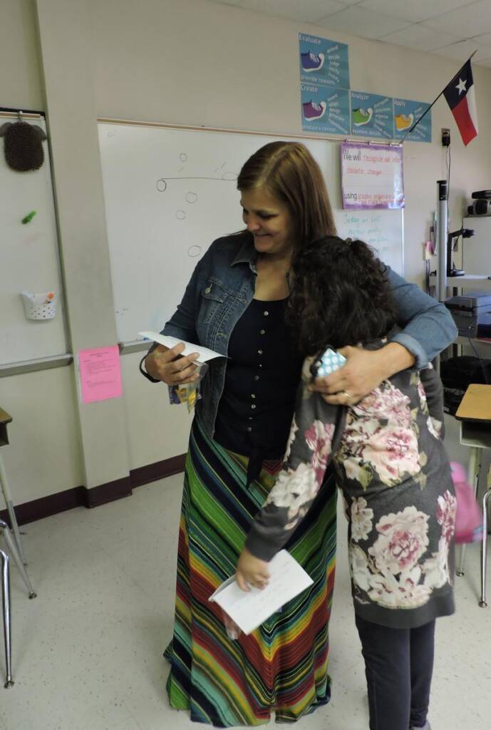 Teacher hugging student in classroom