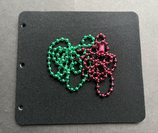 Colored Mardi Gras beads on a black page