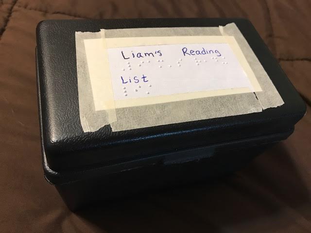 Note-taking card box with label in print and braille "Liam's reading list"