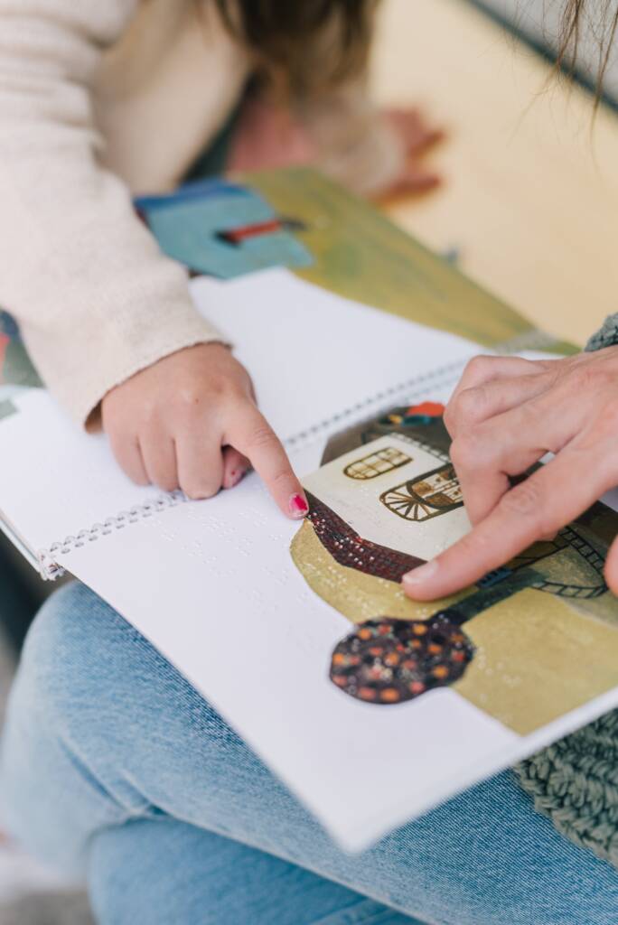 A child and parent pointing to an image on a picture book