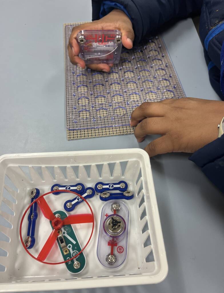 A student's hands assembling pieces from the snap circuits Jr. access kit