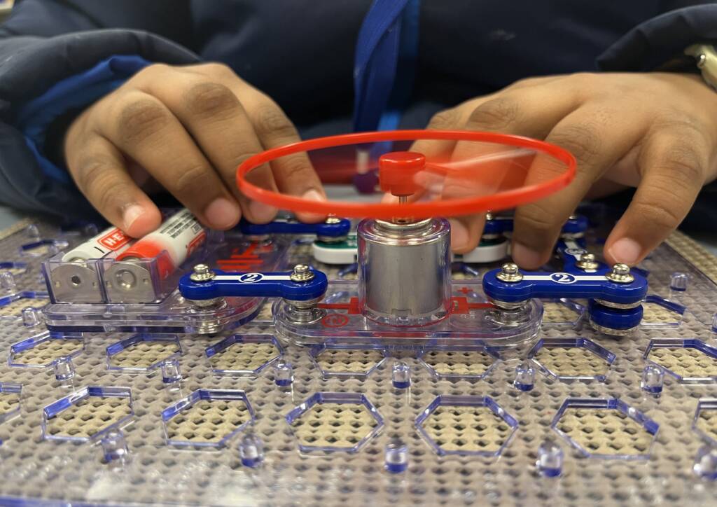 A student's hands using the SNAP CIRCUITS Jr. Access Kit