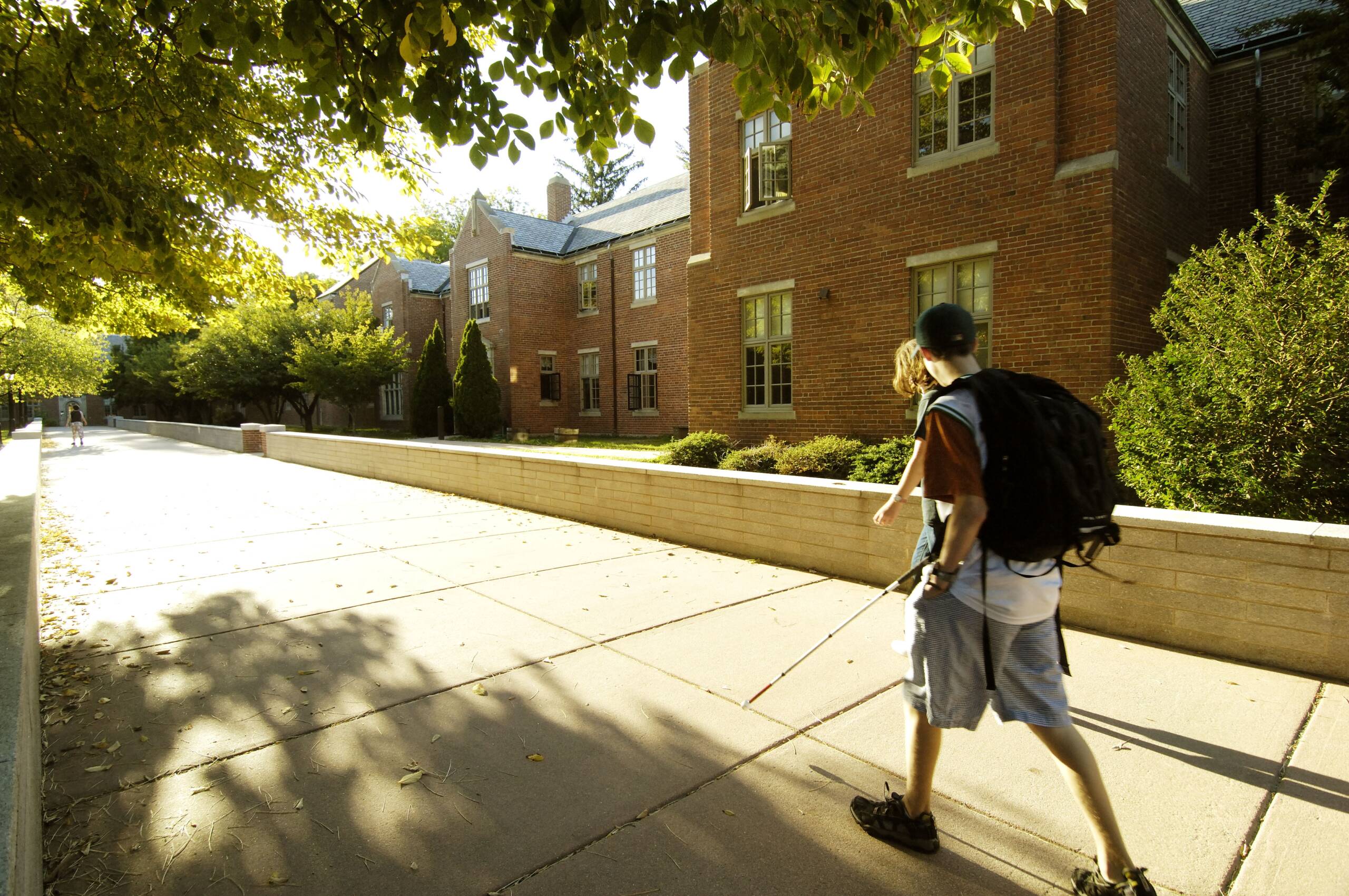 Two students using long canes to travel on sidewalk