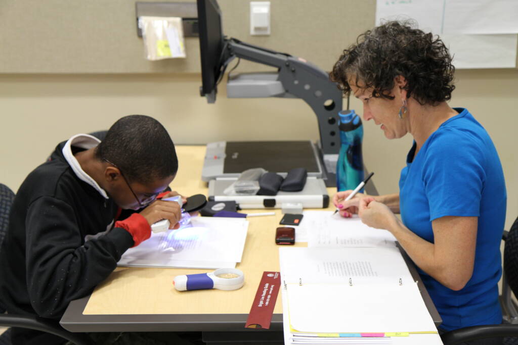 A staff person evaluating a student with low vision