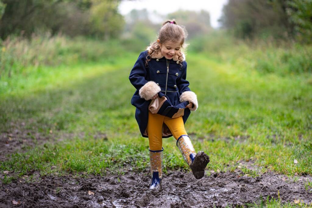 A little girl stepping in the mud.