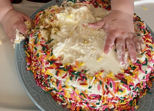 Baby touching a cake and getting messy.