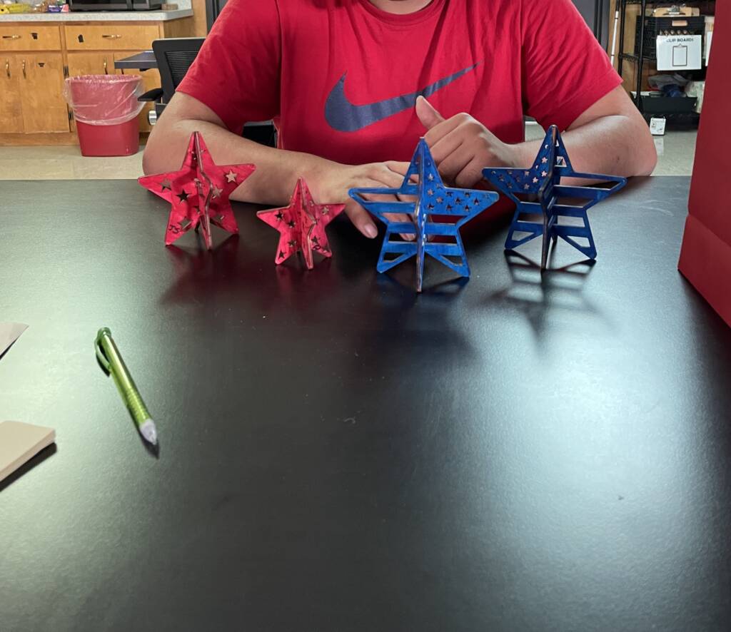 Student showing their completed 3-D painted wooden stars