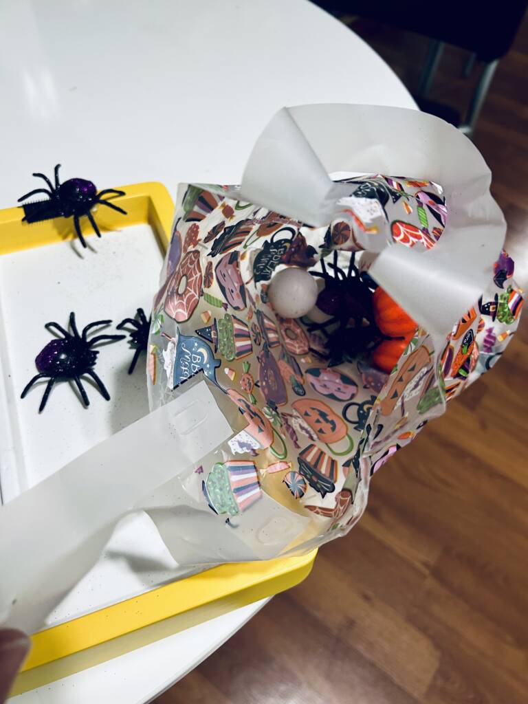 Halloween bag filled with small plastic spiders, pumpkins, and eyes