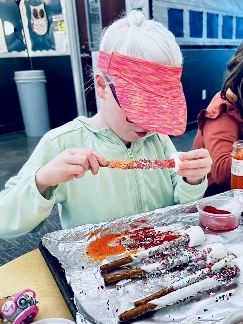 Student putting a marshmallow on a pretzel rod