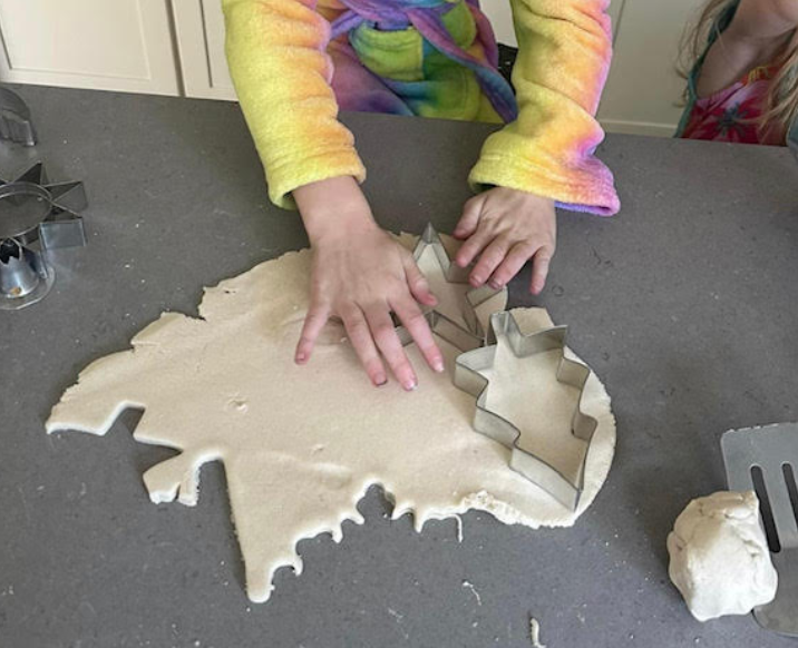 Student using cookie cutters to make a salt dough ornament gift.