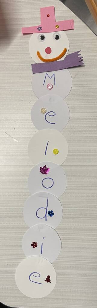 Craft paper snowman with the name Melodie vertically.
