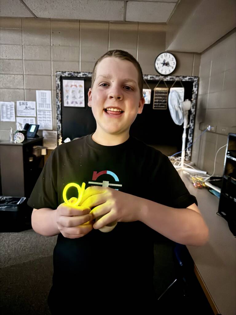 Liam holding up a light up plastic, yellow egg happily.