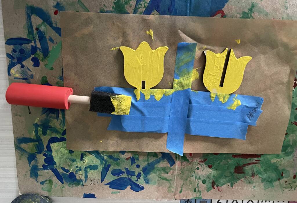 Wooden tulips being painted with a adapted foam brush for easier holding.