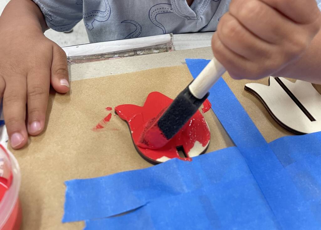 Student painting the wooden tulips red.