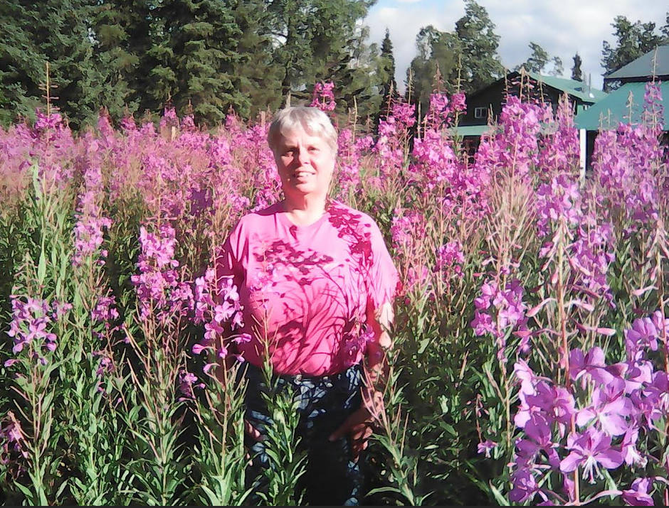 Sandy standing in a field of tall pink flowers.
