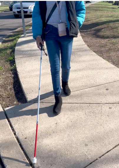 Jessica using a cane on a sidewalk. 