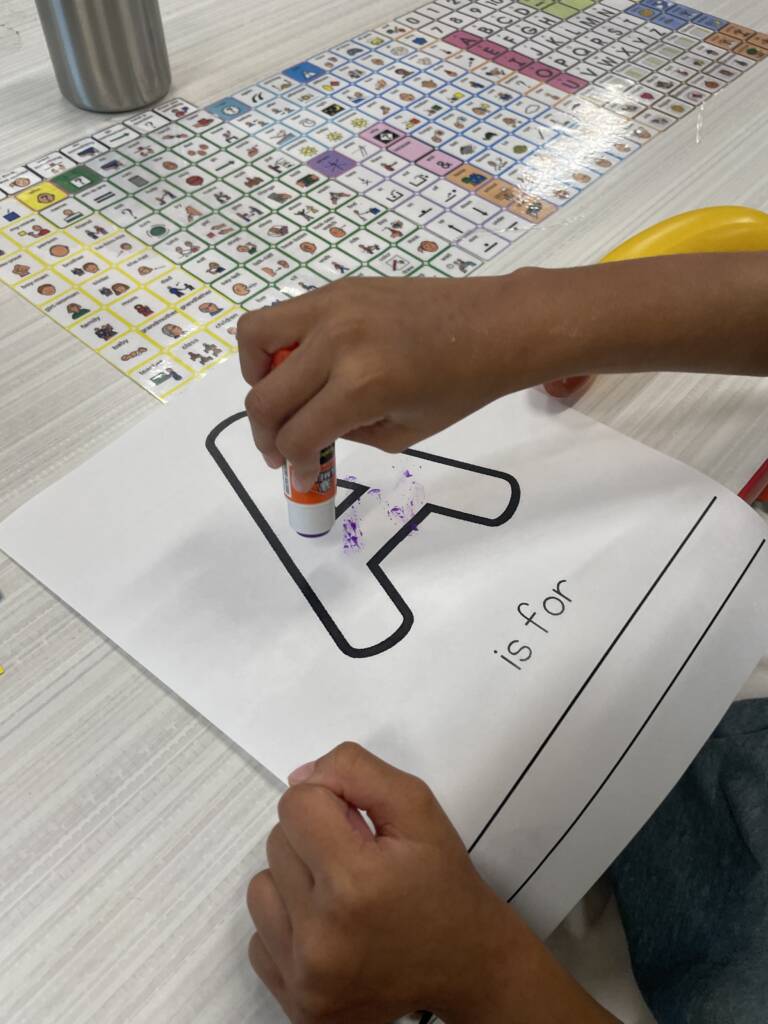Gluing the letter "A" on a sheet of paper.