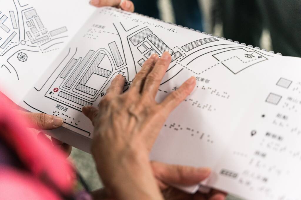 Person using their fingertips to touch a braille map. 