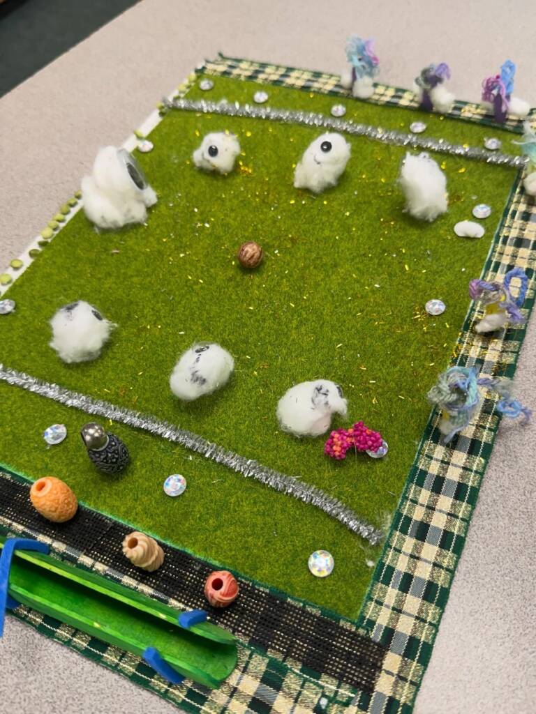 Tactile art of a football field including players, bleachers, and cheerleaders.