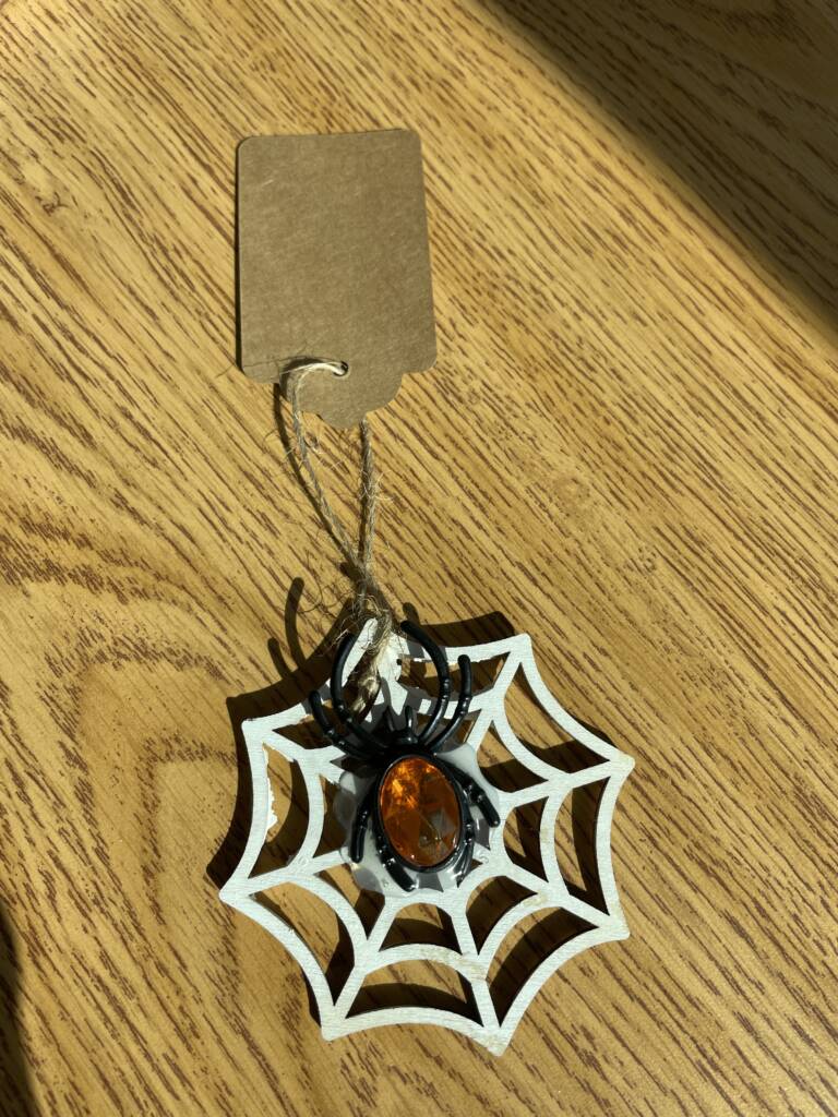 Plastic spider on a wooden web.