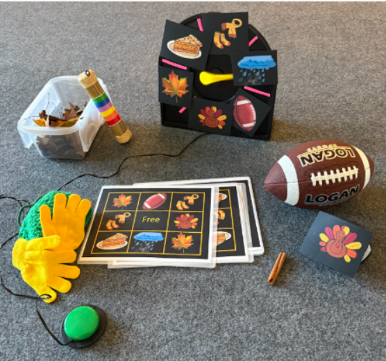 BINGO cards showing pictures of a turkey, pick leaves, football, and gloves with a scarf. Real items are around it and an adapted spinner is used to pick each BINGO space.