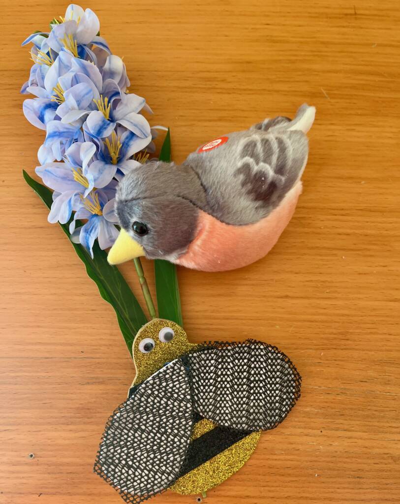 Spring items that include a robin stuffed animal, plastic hyacinth, and a craft made bumble bee