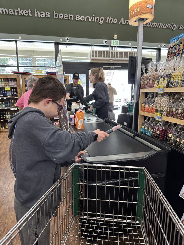 Student at the checkout isle and taking the items out of his cart to pay.  