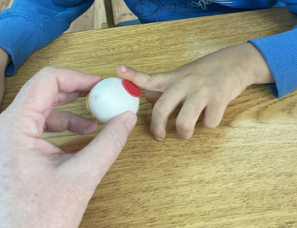 Student placing a foam sticker on an egg.