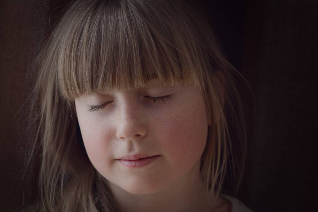 Small girl with eyes closed listening calmly.