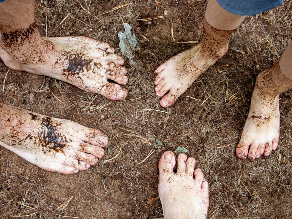 Three sets of bare feet in the dirt.