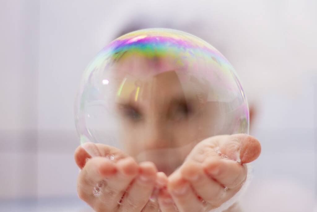 A boy holding a bubble in both hands.
