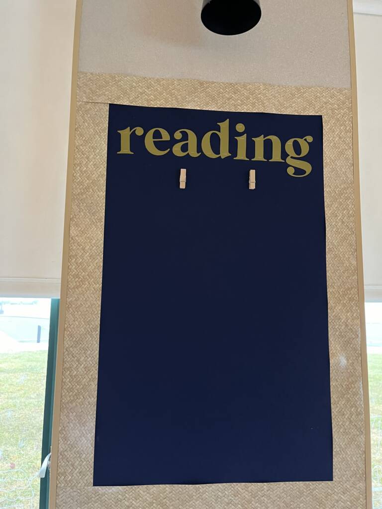Bulletin board with the word reading on it and a black simple background that was in a kindergarten class who had a student with low vision. 