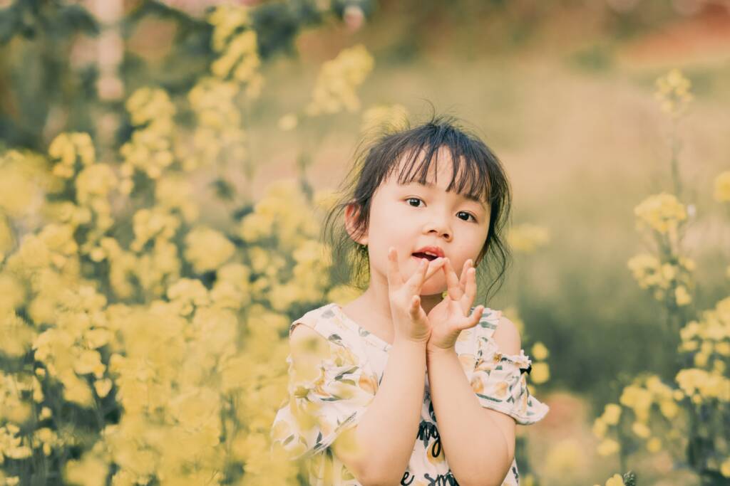 Young girl in a summer dress in a field of yellow wild flowers.