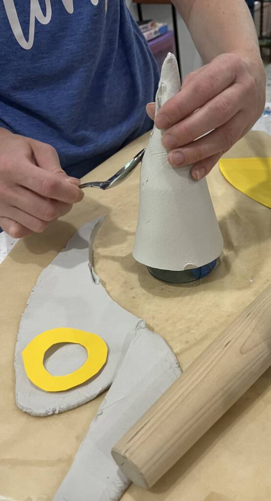 Student shaping the clay to make a ghost with a witch hat.