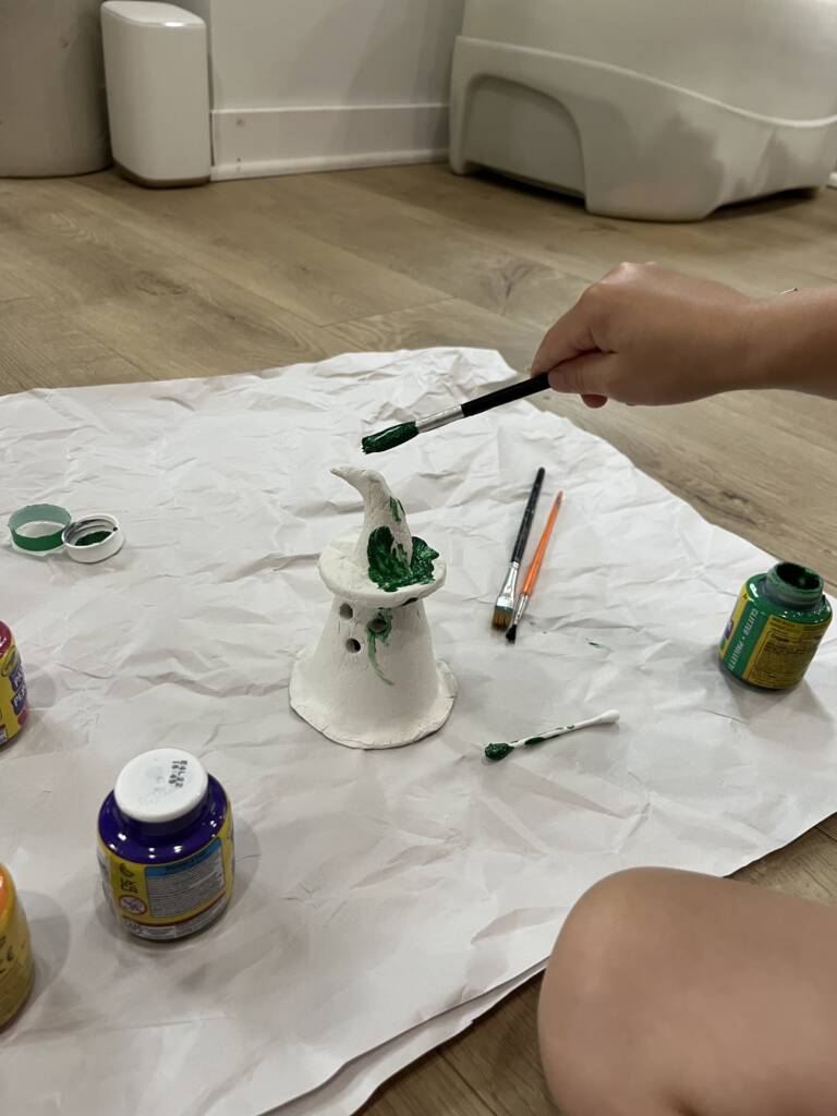 Student painting the clay ghost a glittery green color. 