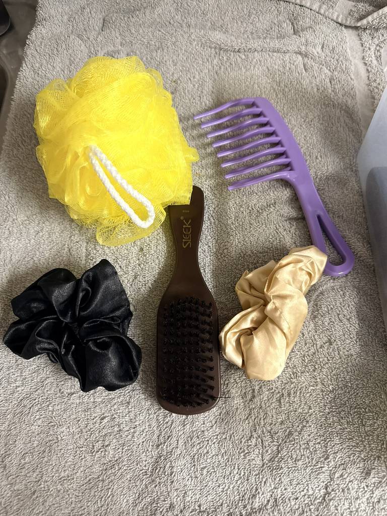 Personal care items that include a comb, hairbrush, sponge, and hair ties.
