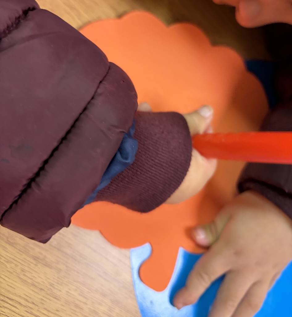 Small child using both hands to create the pumpkin craft.